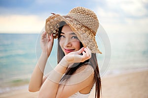 Beautiful girl young woman asia in a  hat smiling on the beach at sunset,enjoy summer vacation on the beach