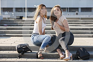 Beautiful girls in a city. Stylish ladies sitting on a stairs
