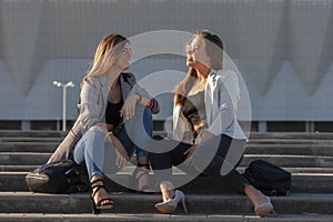 Beautiful girls in a city. Stylish ladies sitting on a stairs