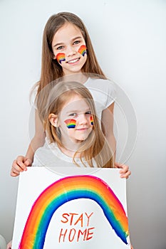 Beautiful girls drew rainbow and poster stay home. photo