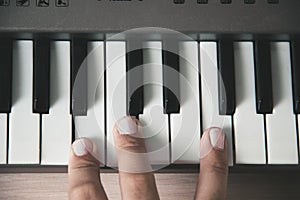 Beautiful girls fingers playing electronic piano keyboards.