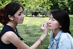 Beautiful girls helping their friend to makeup
