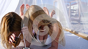 Beautiful girls laughing in beach near ocean seaside, white curtains on bungalow,