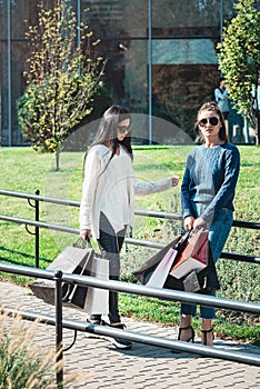 Beautiful girls with paper bags outside shopping mall