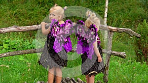 Beautiful girls with purple butterfly wings are standing on the bridge outdoors