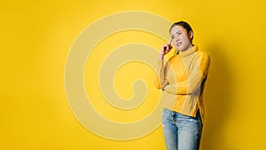 Beautiful girls smiling happy pointing upwards in studio yellow background