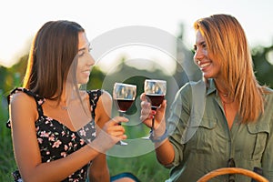 Beautiful girls tasting wine in a field near vineyard field. Celebrating successful harvest season. Couple having a romantic date