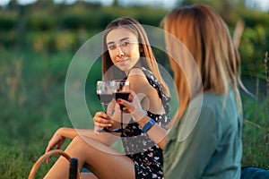 Beautiful girls tasting wine in a field near vineyard field. Celebrating successful harvest season. Couple having a romantic date