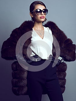 Beautiful glam model wearing white silk blouse, black pants, sable coat, leather gloves and suglasses