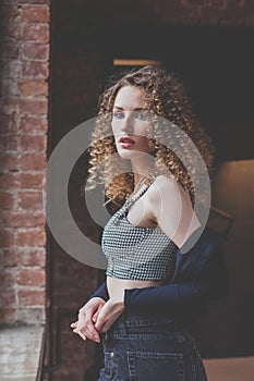 Beautiful glamorous woman in blue jacket with curly hair looking to the camera