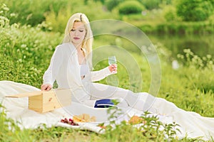 Beautiful glamorous woman with a glass and bottle of wine relaxing in nature at a picnic