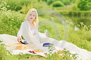 Beautiful glamorous woman with a glass and bottle of wine relaxing in nature at a picnic