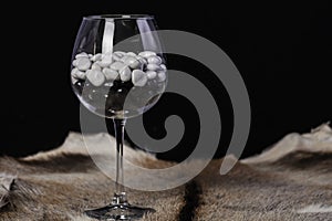 Beautiful glass goblet with black and white stones on a black background