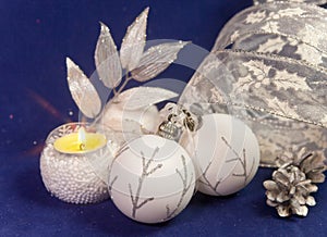 Beautiful glass New Year`s balls, brilliant tinsel, the burning candle on a blue background - New Year`s composition, a card