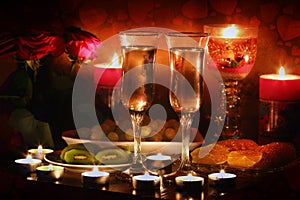 Beautiful glass with rose leafs, rose-petal, rose petals on a romantic date with wine, candles in candlelight and with celebrating