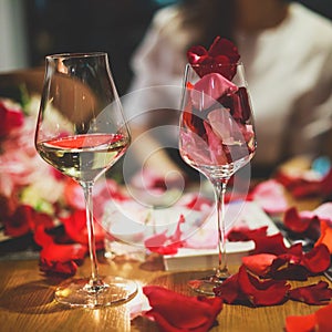 Beautiful glass with rose leafs, rose-petal, rose petals on a romantic date with wine, candles in candlelight and with celebrating