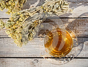 Beautiful glass teacup with Greek mountain herbal Vounou tea tea and dried mountain grass Sideritis syriaca on a wooden table in