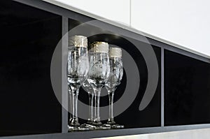 Beautiful glass wine glasses stand on a black decorative shelf