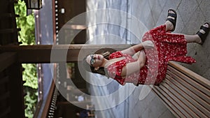 Beautiful, glasses-toting hispanic woman indulging in tranquil solitude while sitting on a bench at tokyo\'s meiji temple, taking