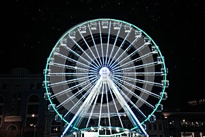 Beautiful glowing Ferris wheel on city street at night