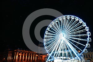 Beautiful glowing Ferris wheel on city street at night. Space for text