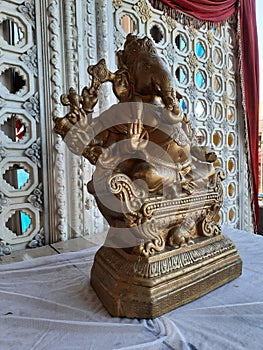 Beautiful gold color Lord Ganesha Statue with Marigold Garland at entrance of Marriage hall or Kalyana Matapa during hindu wedding