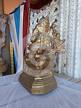 Beautiful gold color Lord Ganesha Statue with Marigold Garland at entrance of Marriage hall or Kalyana Matapa during hindu wedding