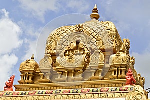 Beautiful gold Hindu ornated temple against a cloudy sky on a sunny day