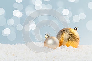 Beautiful golden Christmas balls in the snow on a blue background with bokeh lights. happy new year card