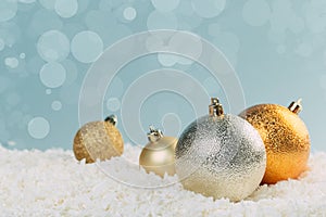 Beautiful golden Christmas balls in the snow on a blue background with bokeh lights. happy new year card