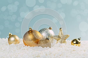 Beautiful golden Christmas balls in the snow on a blue background with bokeh lights. happy new year card