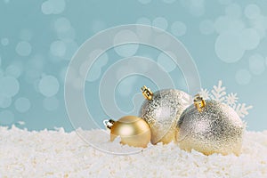 Beautiful golden Christmas balls in the snow on a blue background with bokeh lights. happy new year card