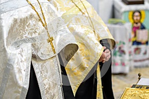 Beautiful golden cross in male hands of priest wearing gold robe on ceremony in christian cathedral church, holy sacramental event