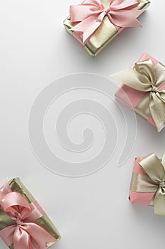 Beautiful golden gifts with pink bows ribbon on white. Christmas, party, birthday background. Celebrate shinny surprise boxes copy