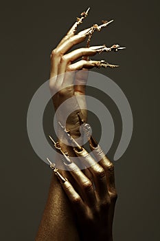 Beautiful golden hands with golden long arty nails. Close up. Studio shot