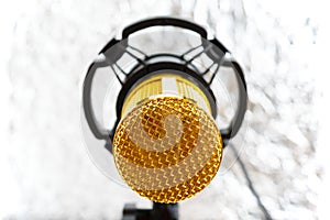 Beautiful golden microphone on a light blurred background