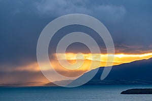 Beautiful golden orange light of sun rise over the mountain with deep blue lake in the morning in raining cloud in Torres del