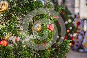 Beautiful golden sparkling ball on artificial Christmas tree. Selective focus. Holiday card with decorations for the New