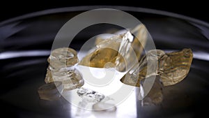 Beautiful golden stones lying in the petri dish on black background. Stock footage. Close up for beige christals lying