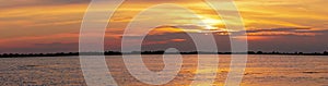 Beautiful, golden sunset in the Danube Delta with light reflected in the lake and clouds in the sky