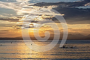 A beautiful golden sunset on the lake Garda, Italy. Silhouette of family playing beach or water ball