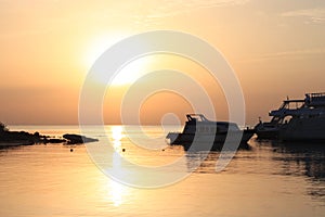 Beautiful golden sunset on the sea. Boats on the water. Warm rays of sun light. Red sea, Egypt