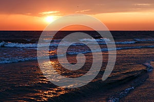 Beautiful golden sunset in the sea with saturated sky and clouds. Reflection in the water. Rocky coastal line. Peaceful serene lan