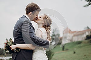 Beautiful gorgeous bride and groom kissing. happy wedding couple hugging and embracing at old castle. happy romantic moments.