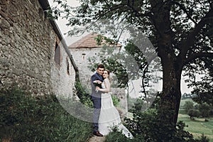 Beautiful gorgeous bride and groom kissing. happy wedding couple hugging and embracing at old castle. happy romantic moments. photo