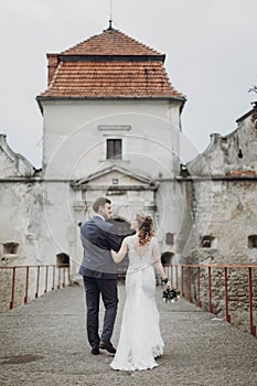 Beautiful gorgeous bride and groom walking. happy wedding couple hugging and embracing at old castle. happy romantic moments.