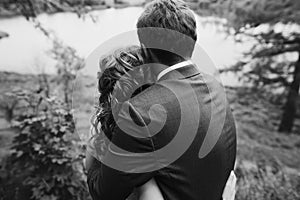 Beautiful gorgeous bride and groom walking in sunny park and embracing. happy wedding couple hugging in green garden. happy