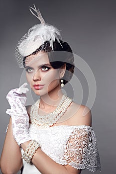 Beautiful gorgeous woman with elegant wavy hairstyle, bright make up. Fashion brunette wearing pearls jewelry, retro hat and lace