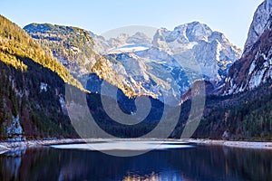 Beautiful Gosausee lake landscape with Dachstein mountains, forest, clouds and reflections in the water in Austrian Alps.