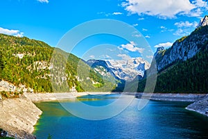 Beautiful Gosausee lake landscape with Dachstein mountains, forest, clouds and reflections in the water in Austrian Alps